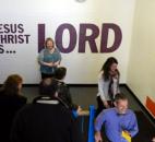 Fourth-grade teacher Susan Murphy stands in front of a wall painted with "Jesus Christ is ... Lord" as a tour passes down the stairs at Emmanuel-St. Michael Lutheran School's Union Street campus Feb. 17. The campus houses grades 3-8 while the Getz Road campus has grades K-2. The school is in its eighth year of growth, with class sizes doubling in each grade through sixth. (Photo by Lisa Esquivel Long of The News-Sentinel)