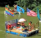 A raft preaching a message of peace makes it way down the St. Marys River Saturday afternoon as part of the Fort Wayne Newspapers Three Rivers Festival Raft Race. Photo by Matthew Glowicki of The News-Sentinel