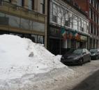 A snowpile outside J.K. O'Donnell's Irish Pub towers many of the cars parked next to it. In some cases, businesses and residents are hiring dump trucks to haul away the snow. (Photo by Jaclyn Goldsborough of The News-Sentinel)