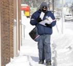 In downtown Fort Wayne streets were nearly empty as most residents stayed home. Scott Stockert, a postal worker, was making his way through snow drifts on North Wells Street on his rounds. Stockert said he was barely keeping warm. (Photo by Ellie Bogue of The News-Sentinel).