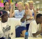 DaMarcus Beasley, seated at left, and his brother Jamar, seated at right, watch a replay of DaMarcus on video from a national game on July 6. Young fans Alyssa Ables, left, Ellie Sommer, center, and Gina Killion applaud his play.