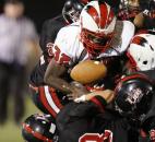 Bishop Luers’ Matt Williamson, bottom, center, rips the football away from North Side running back Anthony Linnear, center, as the Knights defense gang tackles Linnear in the third quarter of their 22-20 win over the Redskins on Friday at Luersfield. (By Chad Ryan of INMedia Source)