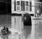 Residents boat down West Superior Street past car repair shop Fox & Fox's famous giant tire, center, which would later have the high-water line painted on it. The tire was eventually moved to a stand adjacent to the automotive shop, and a high-water marker took its place.