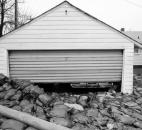 Sandbags from the Pemberton dike engulf a garage. Sandbaggers widened the base of the sandbag wall into the yard in order to stop the water that was seeping under the dike.