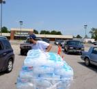 A volunteer hands out bags of ice to area residents Sunday in the former Value City Department Store parking lot near the intersection of Coliseum Blvd. and Lake Avenue. Volunteers from AEP and Community Harvest Food Bank gave two bags per household to those cars that lined up. WalMart donated the bags of ice, enough to fill a semi trailer. (Photo by Sarah Janssen)
