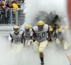 The Bulldogs take the field through a cloud of smoke, from fire extinguishers, at the beginning of Friday night’s game at New Haven. The game was called in the third quarter due to lightening and will resume Saturday at 3 p.m. (Photo by Ellie Bogue of The News-Sentinel)