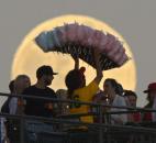A cotton candy vendor, center, walks in from of the moon during the Los Angeles Angels' baseball game against the Pittsburgh Pirates on Saturday in Anaheim, Calif. 