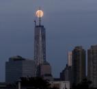 The moon is seen in its waxing gibbous stage Saturday as it rises over Lower Manhattan, including One World Trade Center, center. The moon, which reached its full stage Sunday, was expected to be seen 13.5 percent larger than usual during a phenomenon known as supermoon. 