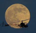 A full moon rises Saturday behind the helicopter from the original Batman television show, which people can ride at the New Jersey State Fair, in East Rutherford, N.J.  