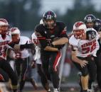 Bishop Luers running back Nick Morken, center, bursts between North Side’s Josh Fleming, left, and Dustin Gregory during the first half of the Knights’ 22-20 win on Friday at Luersfield. (By Chad Ryan of INMedia Source)