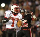 North Side quarterback C.J. Jackson, left, rolls out of the pocket as Bishop Luers’ Everett Green chases him during Friday’s game at Luersfield. (By Chad Ryan of INMedia Source)