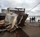 People walk near a storm-damaged home along the waterfront in the aftermath of Sandy on Tuesday, in Milford, Conn. Sandy, the storm that made landfall Monday, caused multiple fatalities, halted mass transit and cut power to more than 6 million homes and businesses. Photo by Brian A. Pounds