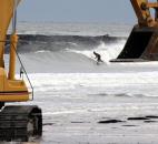 Surfers take to the water as work begins at removing debris at the approach to the old Indian River Inlet bridge in the wake of Sandy, Tuesday afternoon, in Bethany Beach, Del. Photo by William Bretzger