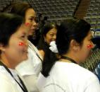 Burmese women wear stickers with Aung San Suu Kyi’s National League for Democracy flag Tuesday morning at Memorial Coliseum during preparations for the democracy leader’s speech. By Lisa Esquivel Long 