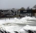 Ocean waves kick up near homes along Peggoty Beach in Scituate, Mass., on Monday. 