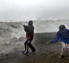 Youngsters run as waves crash against a seawall in Scituate, Mass., on Monday. 