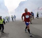 A Boston Marathon competitor and Boston police run from the area of an explosion near the finish line in Boston. Photo by By The Associated Press