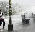 A woman reacts to waves crashing over a seawall in Narragansett, R.I., on Monday.  